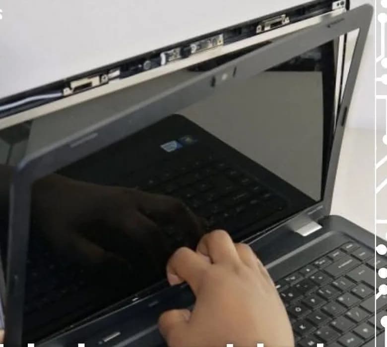 Técnico soltando a moldura da tela de um notebook aberto sobre a bancada.